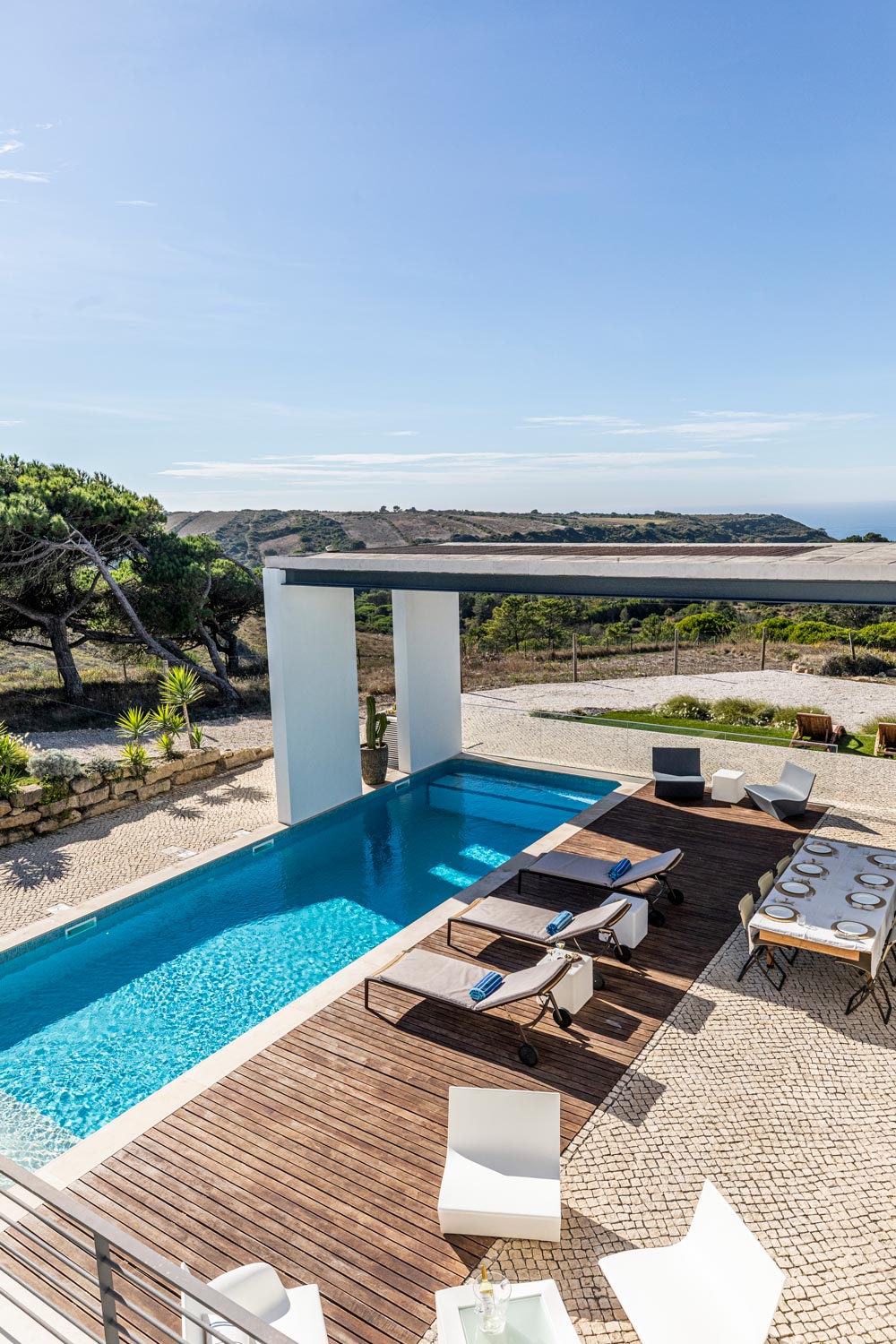 Luxury outdoor seating area with wooden pergola and comfortable cushions overlooking scenic landscape